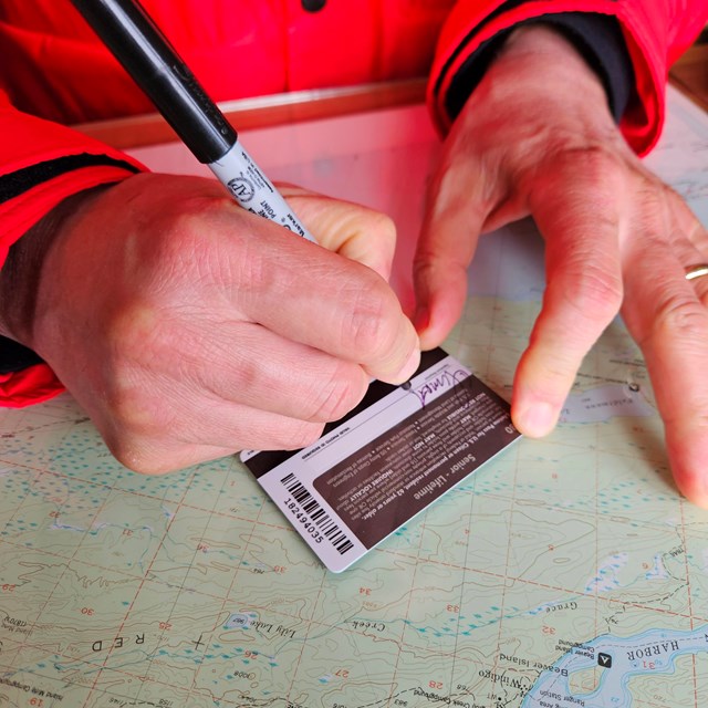 Someone signing the back of a pass with a pen.