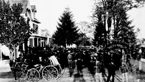 Photo of a crowd gathering at the front porch of Garfield's home.q