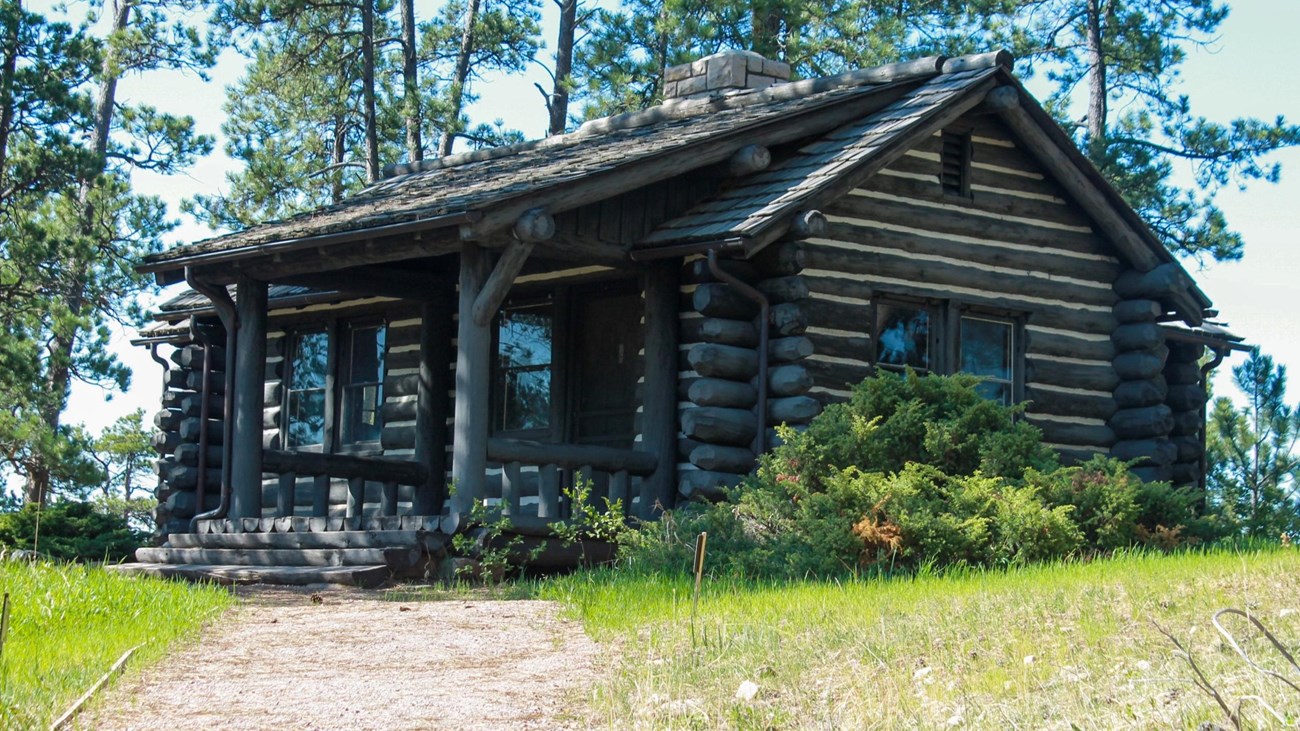 A log cabin with gravel path and grass