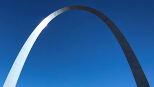 the steel Gateway Arch curving against a blue sky