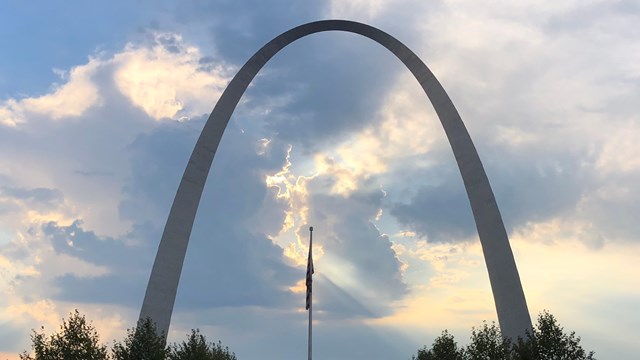 silhouette of the Gateway Arch against blue and yellow clouds at dawn