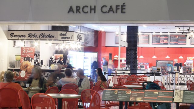 People sitting at tables eating in front of the Arch Cafe.