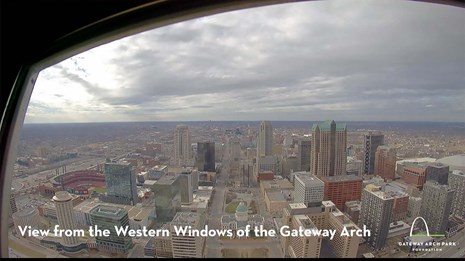 A city view on a hazy day. "View from the western windows of the gateway arch" is printed in white.