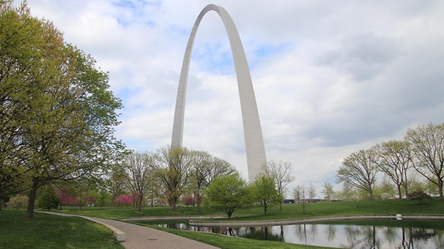 The Gateway Arch, with a walking path and a pond in the foreground