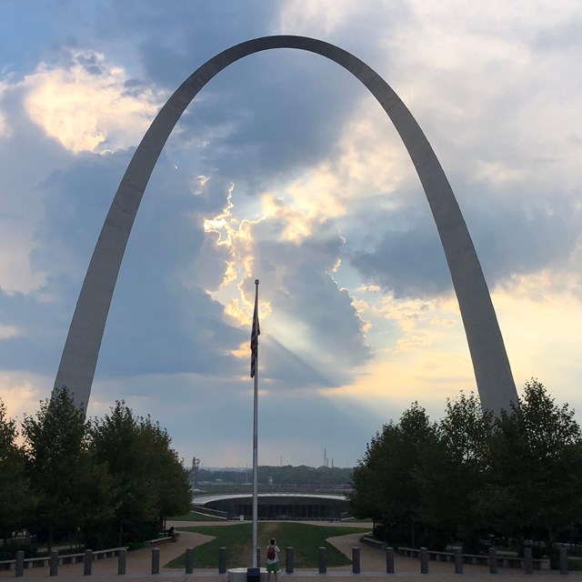 silhouette of the Gateway Arch against blue and yellow clouds at dawn