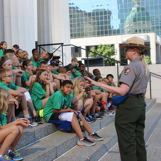 Park Ranger presenting to students sitting on steps of the Old Courthouse.