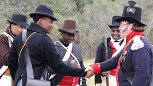 Men dressed as War of 1812 era soldiers shake hands