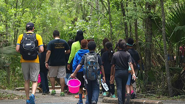 group of kids walking with science equipment along a trail