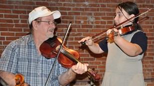 Man and little girl playing fiddles
