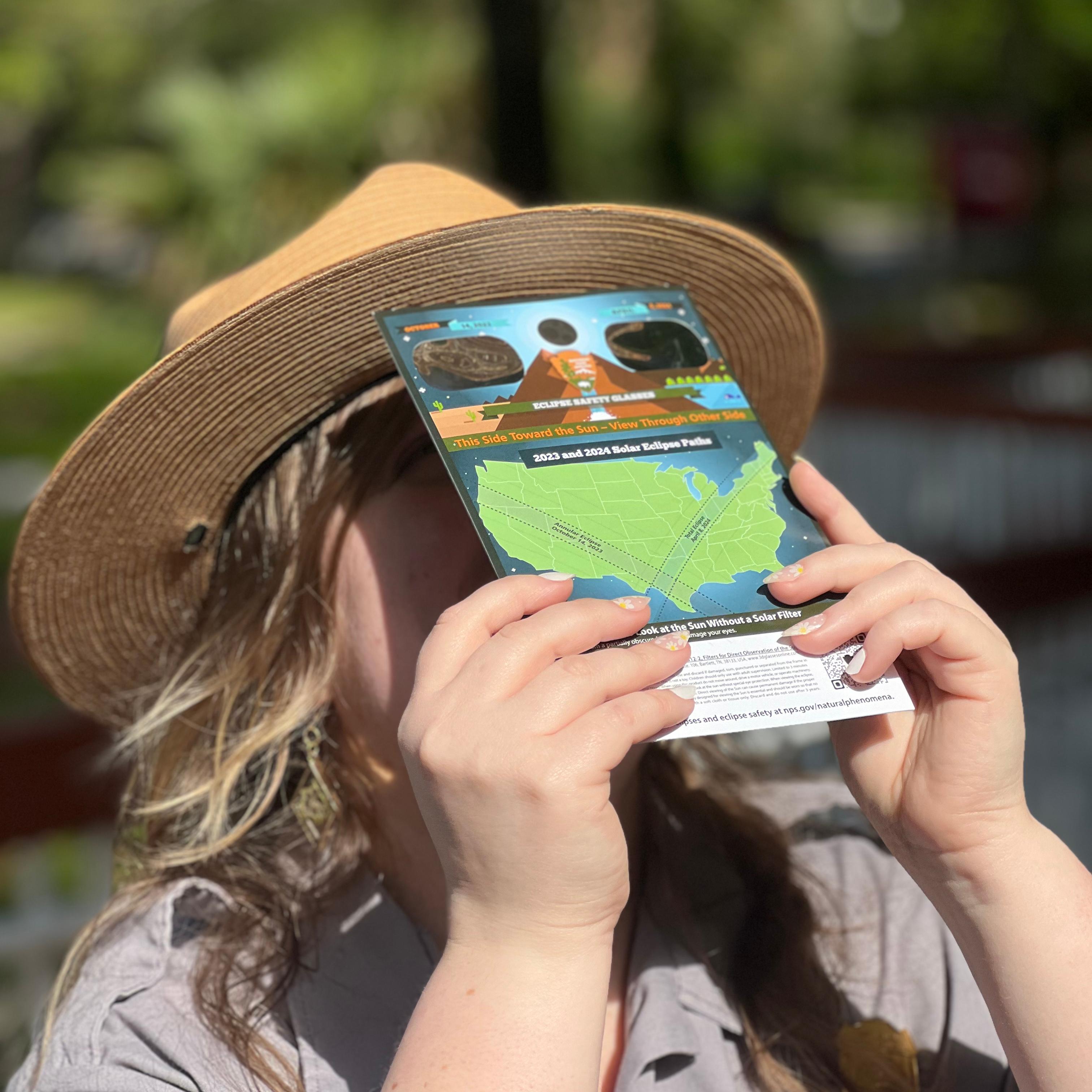 A park ranger looks at the sun through eclipse glasses.