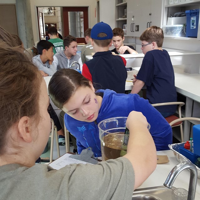 Two girls look at a science beaker.