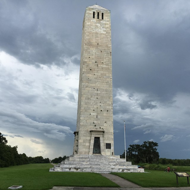 Tall stone monument column with a dark, cloudy sky.