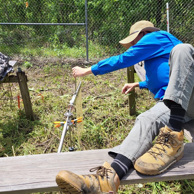 A man reaches out to take scientific measurements outside.