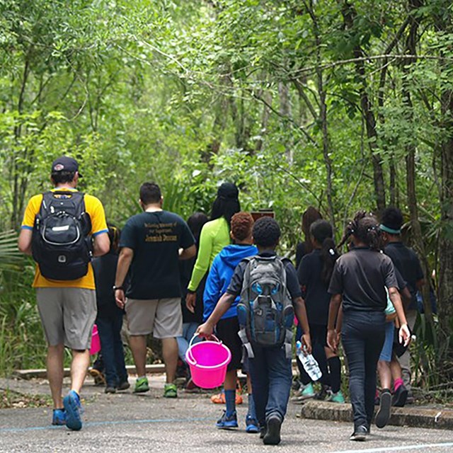 A group of campers walking with science equipment along a trail. 