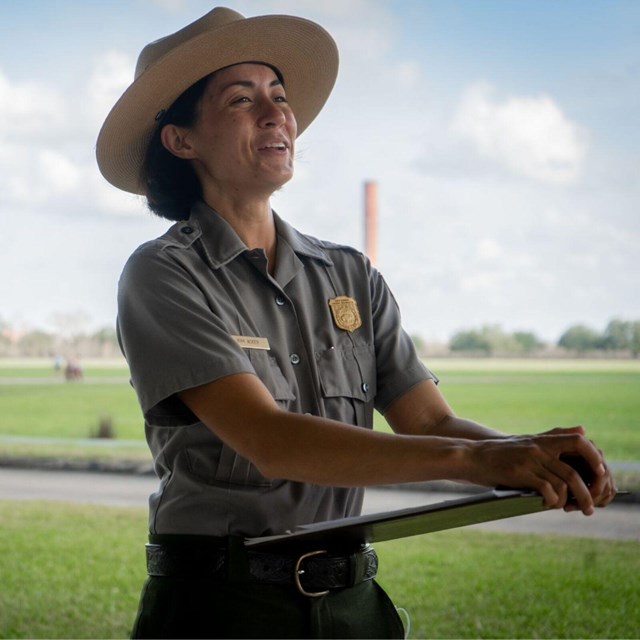 Park ranger smiles and holds a clip board.