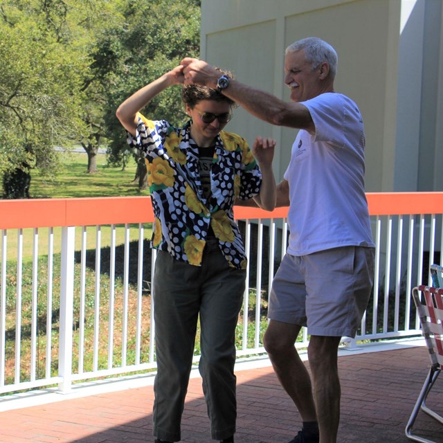 A couple dancing on a sunny porch.