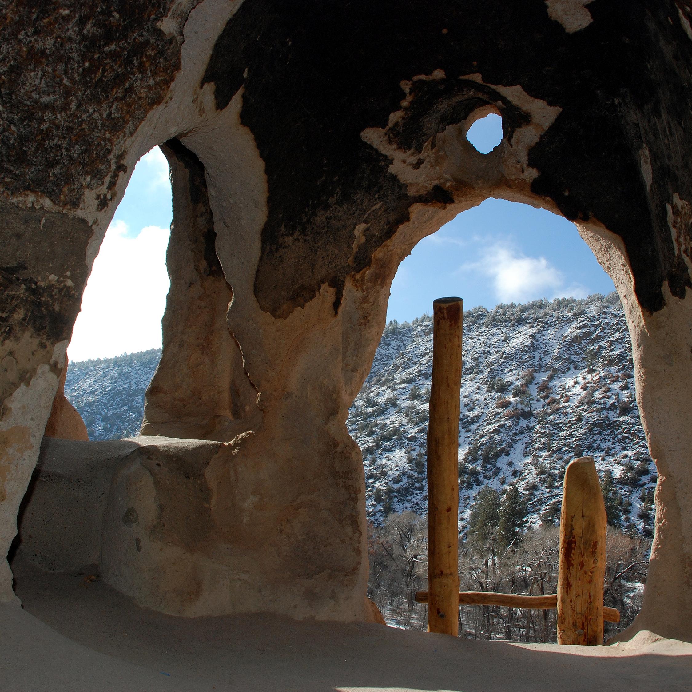 Looking out into a canyon from a small cavate with a wooden ladder.