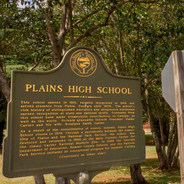 A historic marker stands outside the entrance to Plains High School