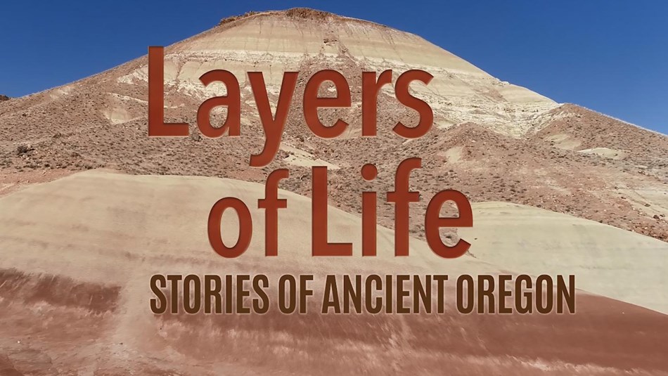Layers of Life, Stories of Ancient Oregon text is over red and gold layered rocks