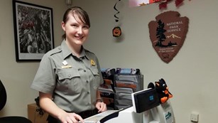 Female Ranger stands behind a cash register. 