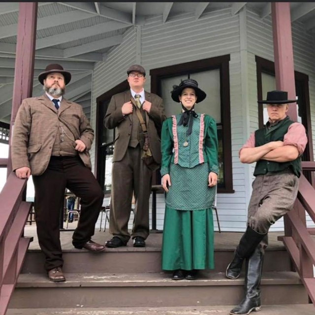 Park rangers in period clothing on the porch of the club house.