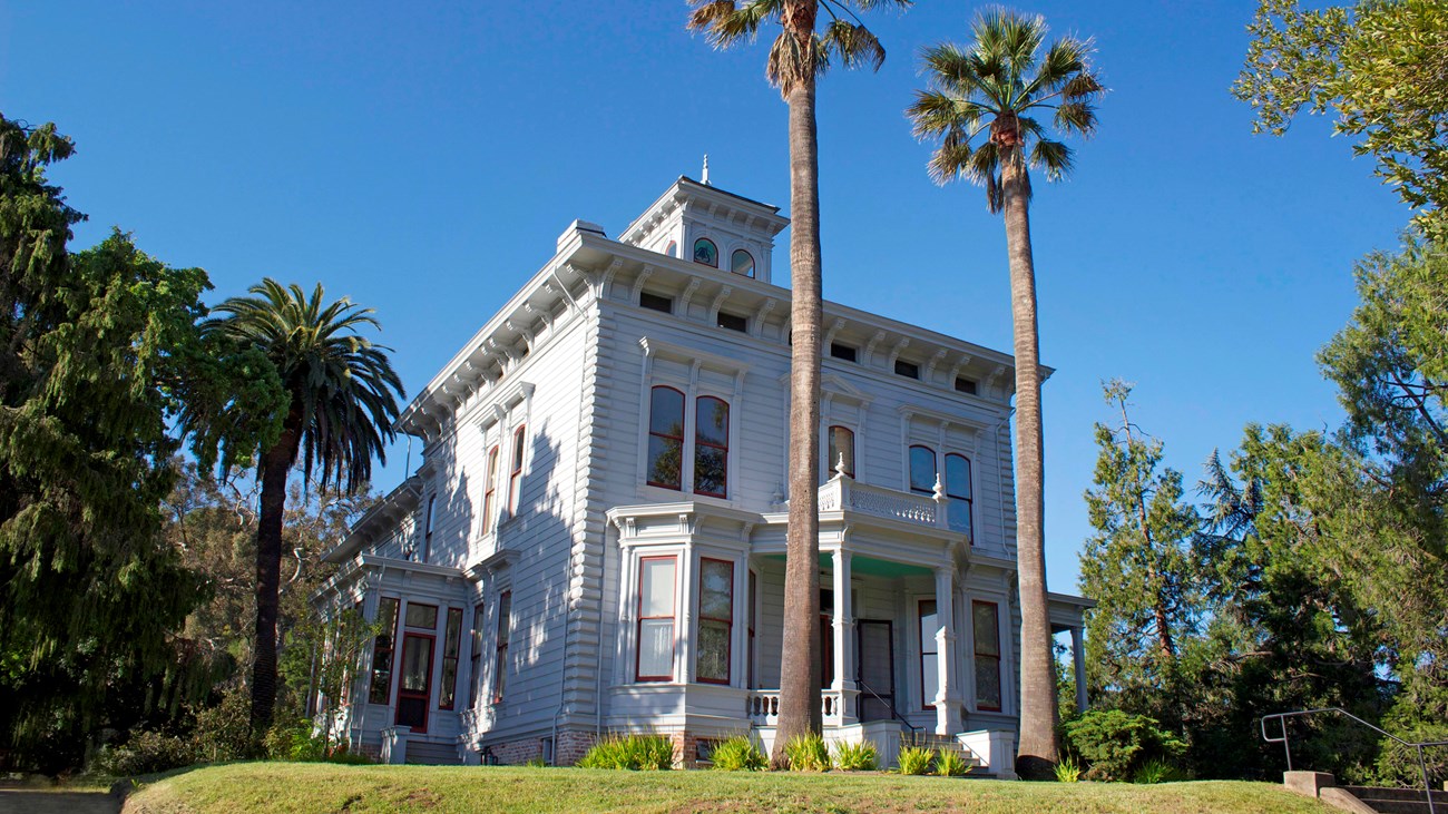 Photograph of the Strentzel/Muir home. Trees on all sides of a victorian two story home.