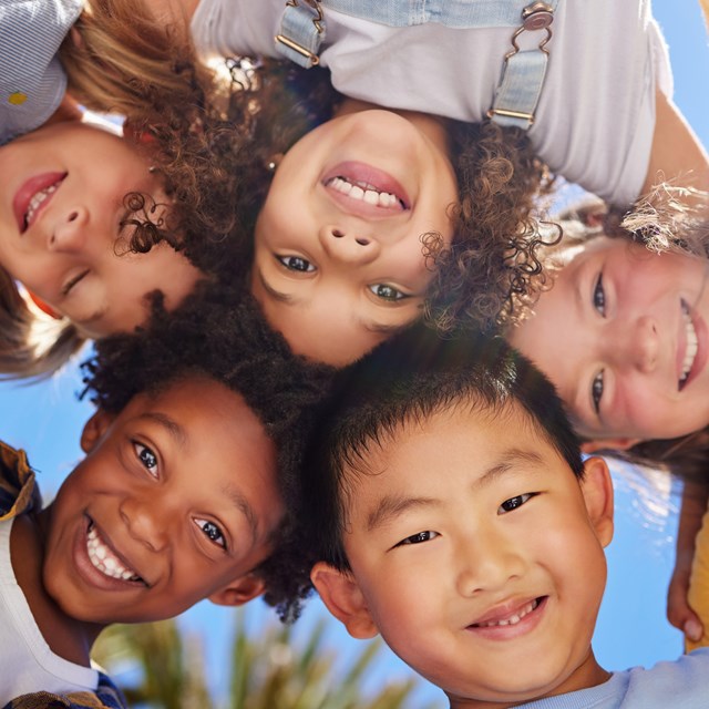 A group of young kids huddle and smile at the camera. 