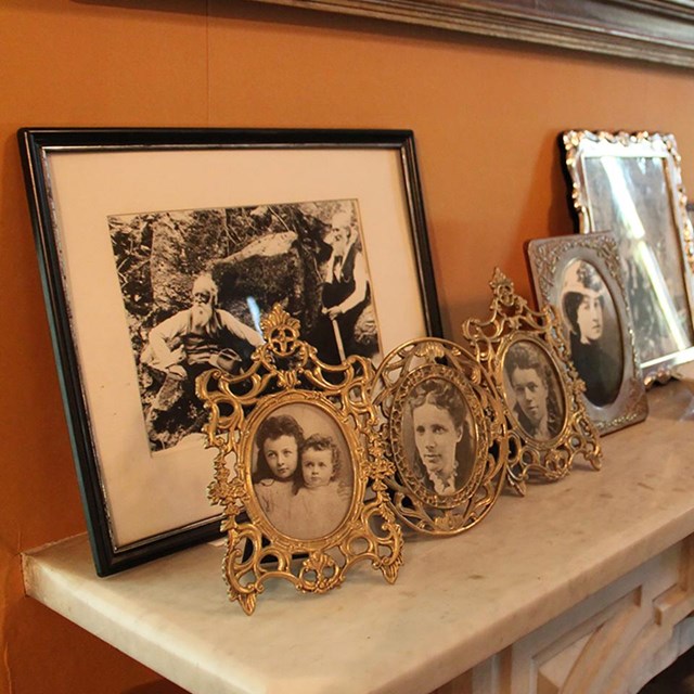 Fireplace mantel with multiple picture frames including photos of family.