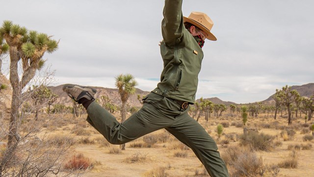 A park ranger jumps through the air.