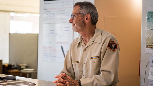 A volunteer stands behind a front desk at a visitor center. 