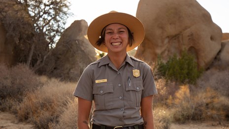 A park ranger smiles at the camera in the desert