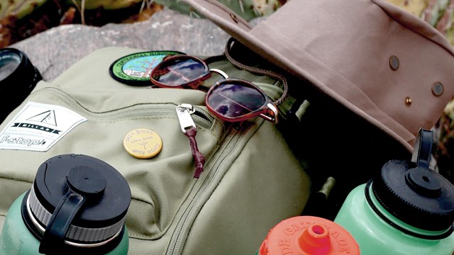 a backpack with water bottles, a hat, and sunglasses