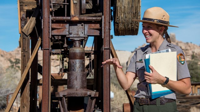 A ranger presentation in front of a piece of wooden and metal machinery.