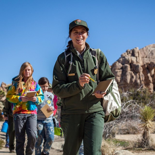 A ranger on a trail with students following