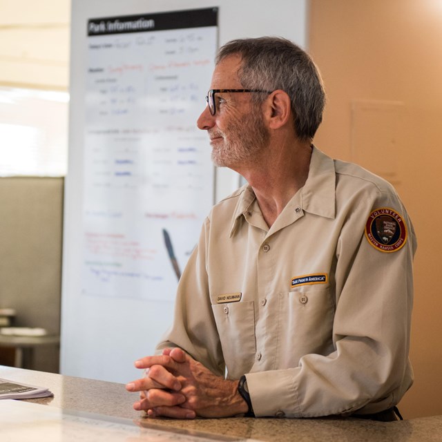 A volunteer smiles softly while at the visitor center desk