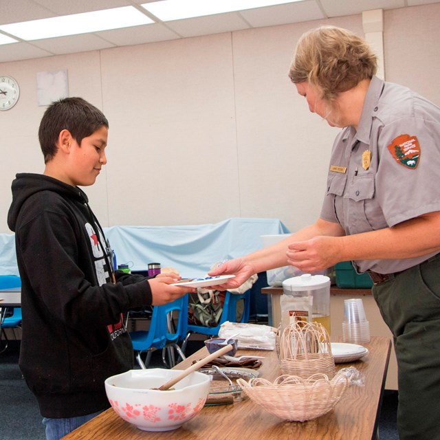 A ranger holds out an item for a student to see.