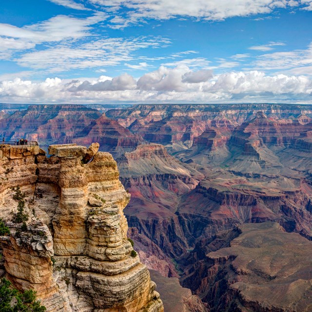 a complex canyon system with clouds and blue sky in the background