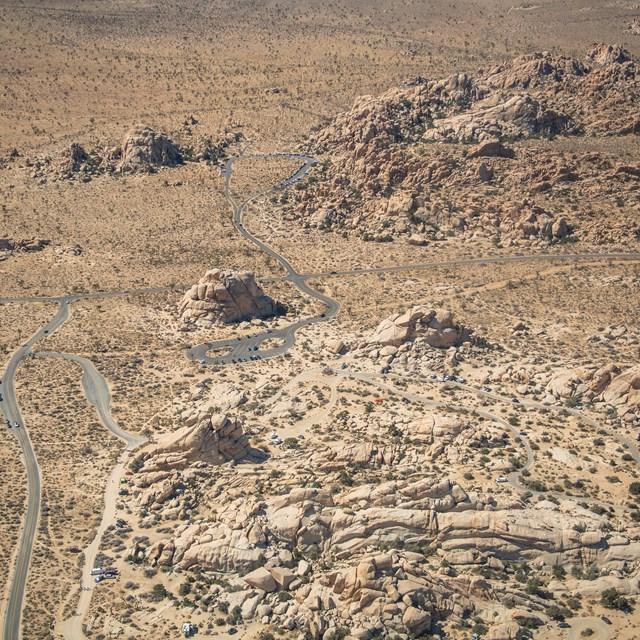 an aerial view of rocks, roads, and the desert floor. 