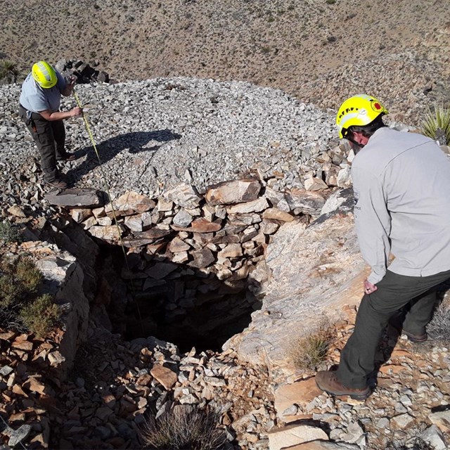 Two rangers looking down into a mine shaft