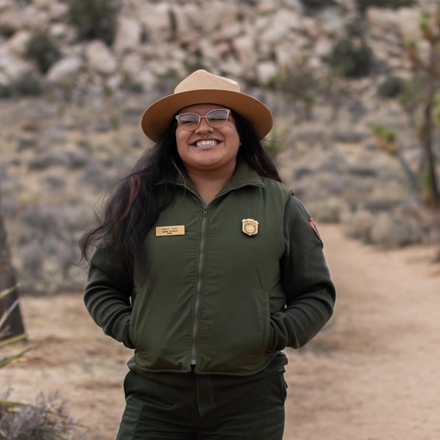 Park ranger smiling with blurred backdrop.