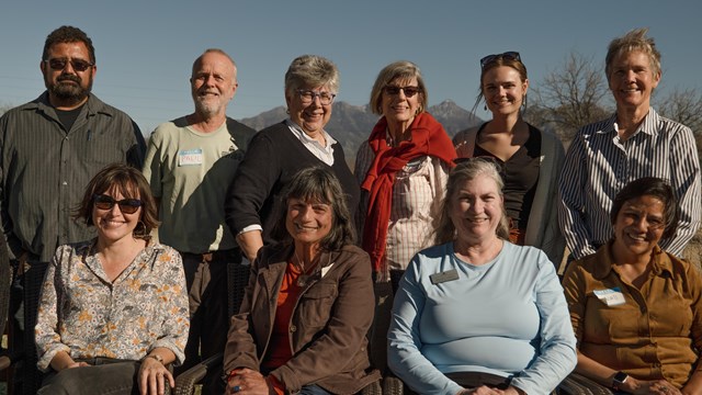 A group of people stand and sit together to pose for a photo