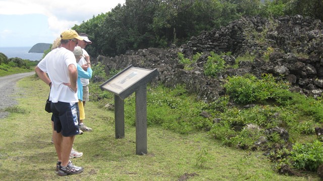 a few people look at an informational, wayside sign