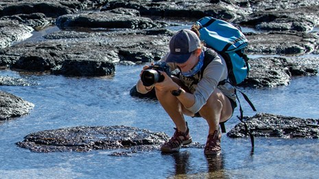 A photographer on a rocky beach 