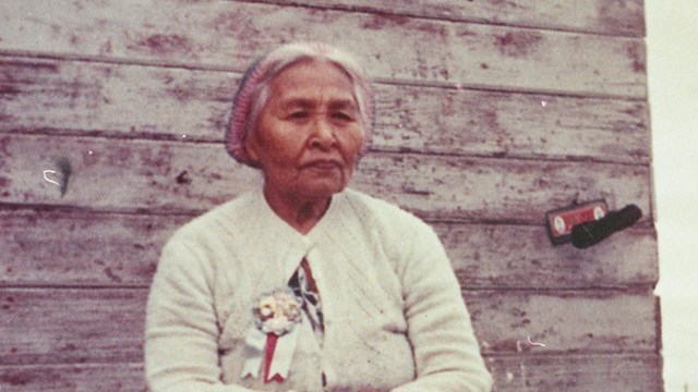 Woman sitting with side of building behind her