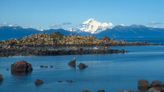 Rocky coastline with mountains in background.