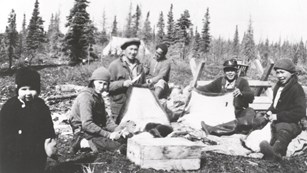 A historic photo of six people at a camp site.