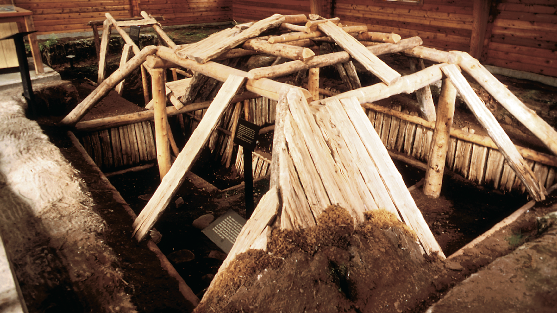 A semi-subterranean home reconstruction inside of a wooden structure.