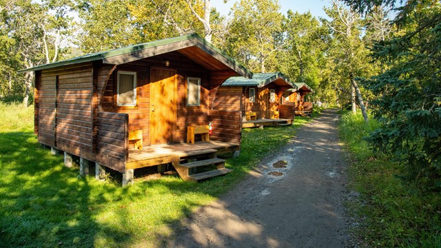 3 panabode style cabins are on a grassy lawn