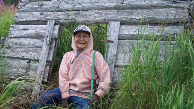 A woman sits in front of part of an old building