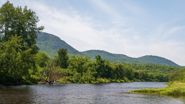 Forest-covered mountains visible along a smooth-flowing section of the East Branch Penobscot River.